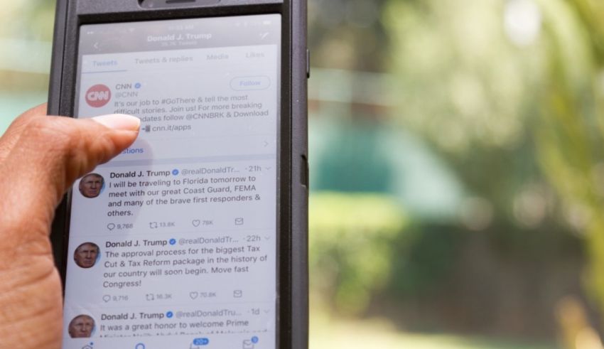 A person holding a cell phone with a tweet on it.