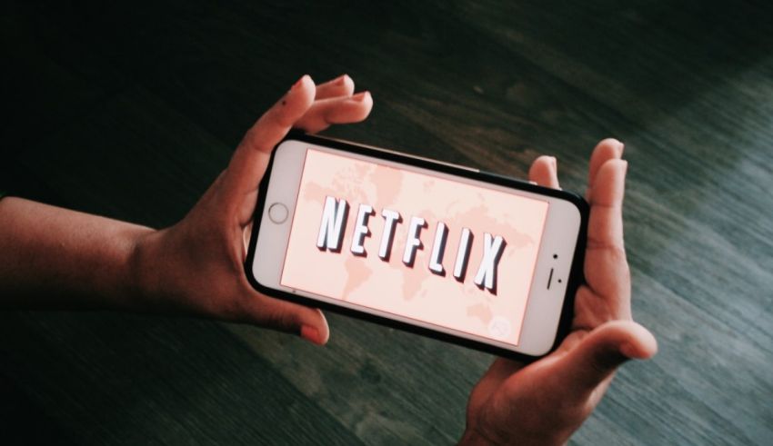 A person holding up a phone with the netflix logo on it.