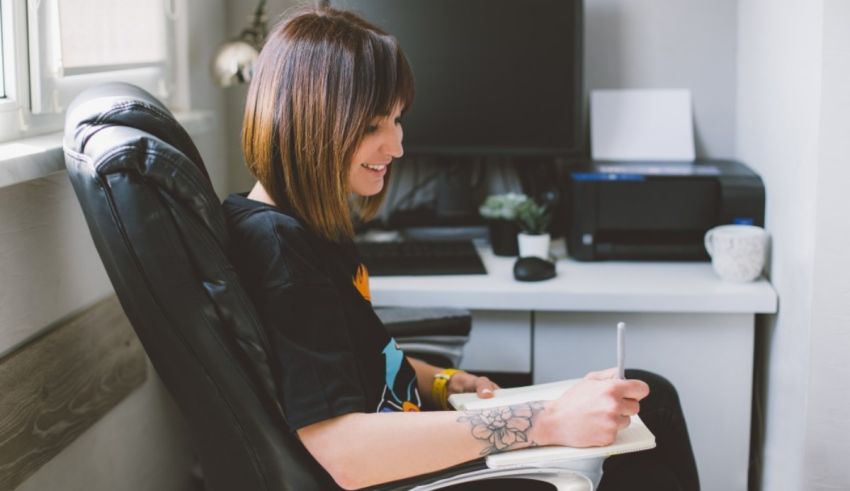 A woman sitting in an office chair writing in a notebook.