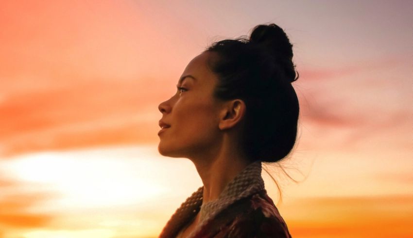 A woman is standing in front of a sunset.