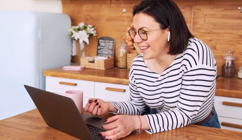A woman sitting at a kitchen table using a laptop.