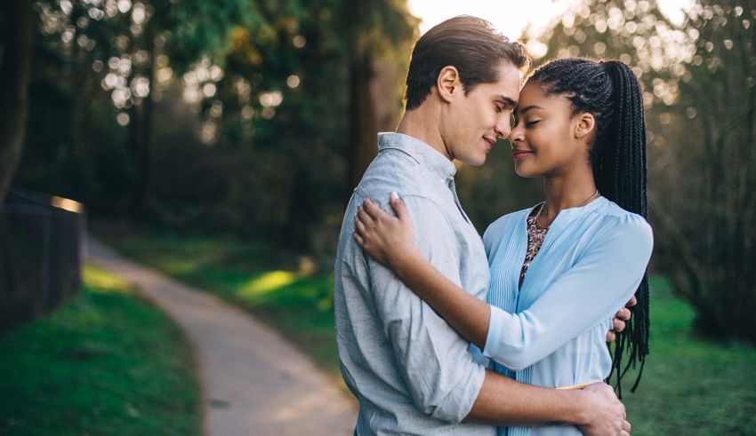 A couple embracing on a path in the woods.