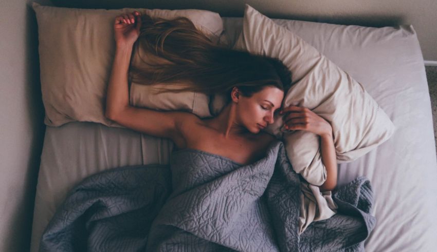 A woman laying in bed with a blanket on her head.
