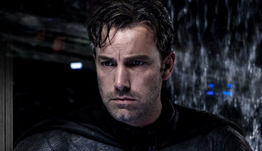 The batman is standing in the rain.