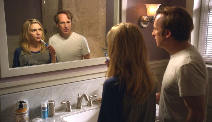A man and a woman brushing their teeth in front of a mirror.