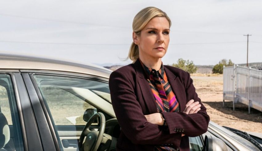 A woman standing in front of a car with her arms crossed.