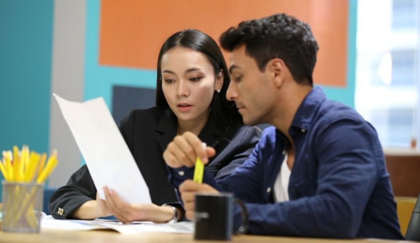 A man and woman sitting at a table looking at papers.