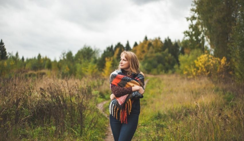 A young woman in a scarf standing in a field.