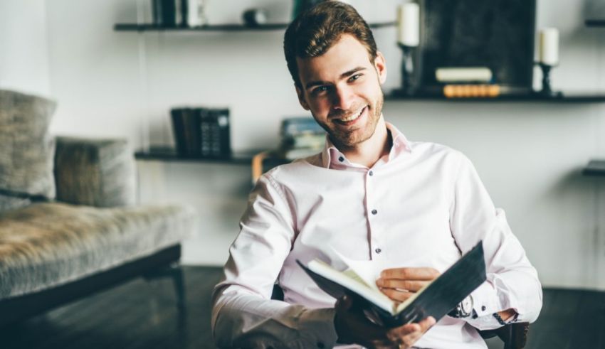 A man is sitting in a chair and reading a book.