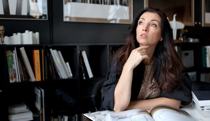 A woman sitting at a desk looking at a book.