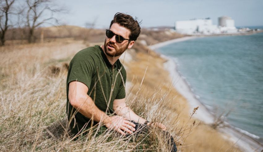 A man sitting on a grassy hill near the water.
