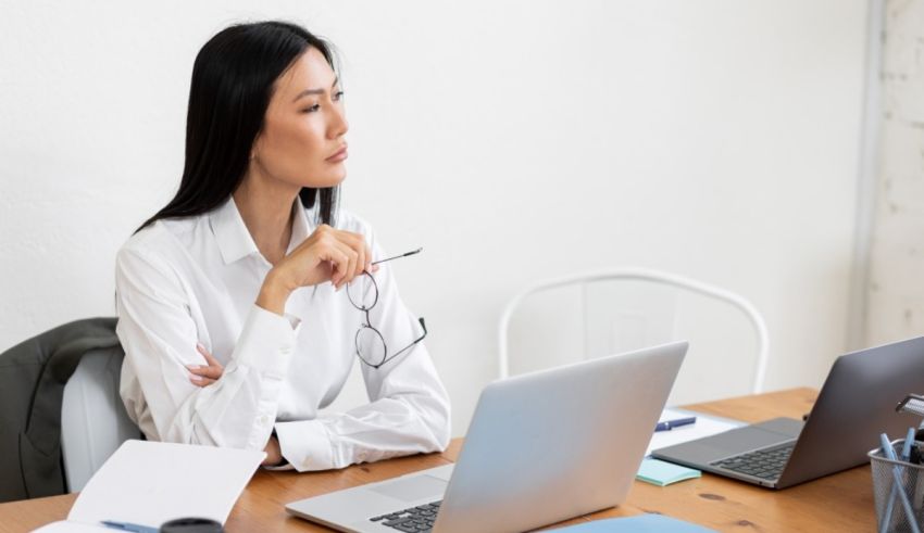 A woman sitting at a desk looking at her laptop.