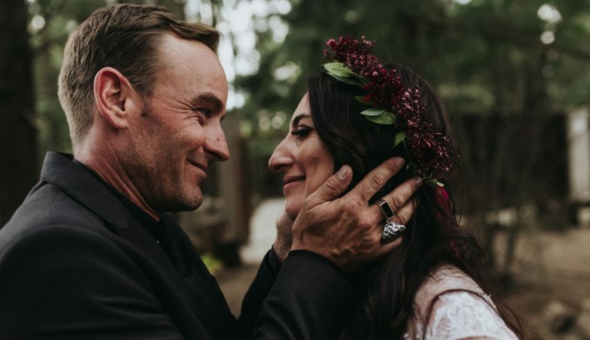 A bride and groom embracing in the woods.