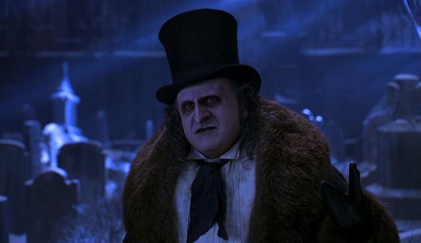 A man in a top hat is standing in a cemetery.