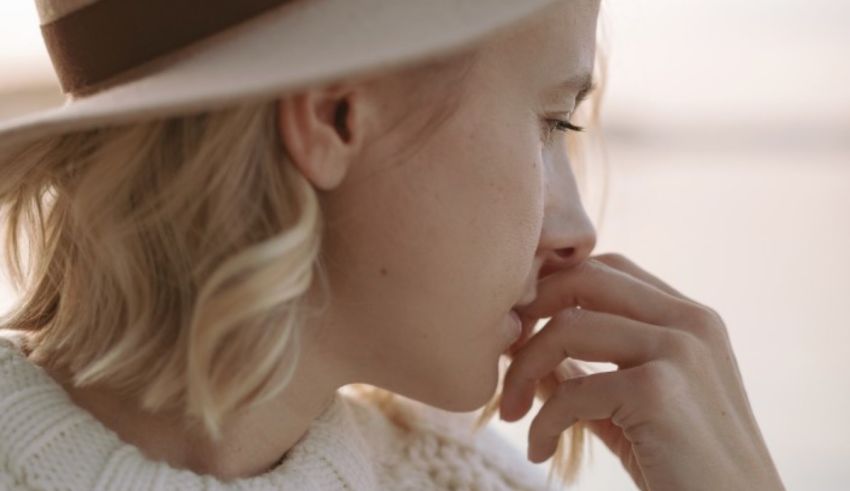 A woman wearing a hat is looking at the water.