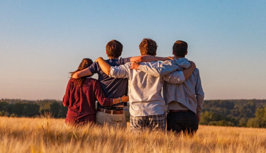 Four friends standing together in a wheat field.