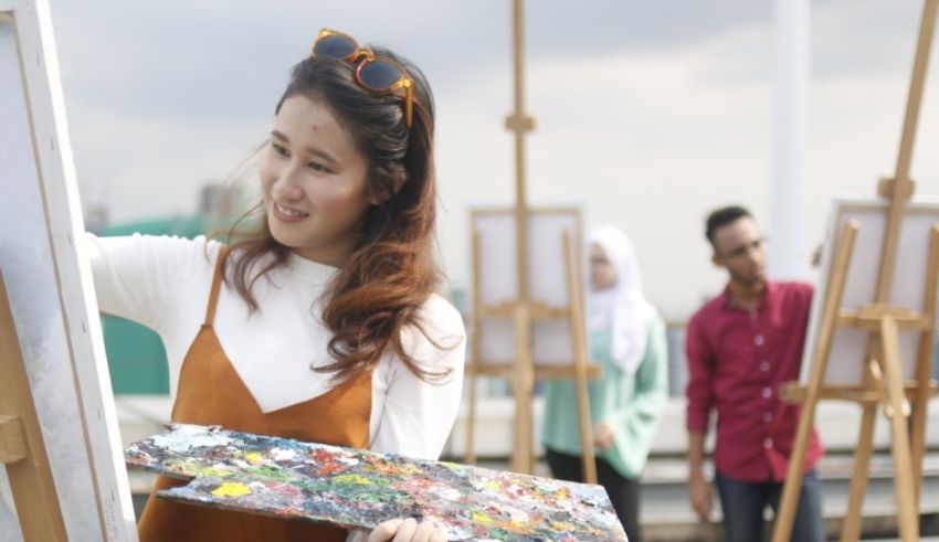 A woman is painting on an easel in front of a group of people.