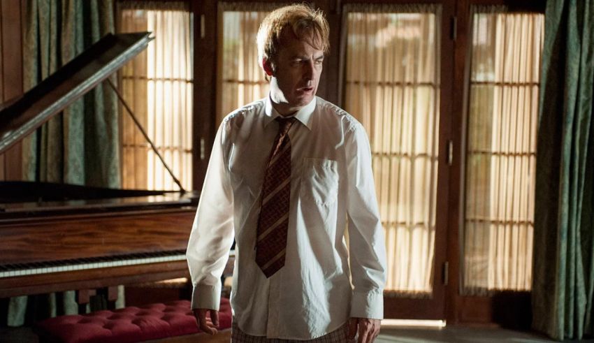 A man in a white shirt and tie standing in front of a piano.