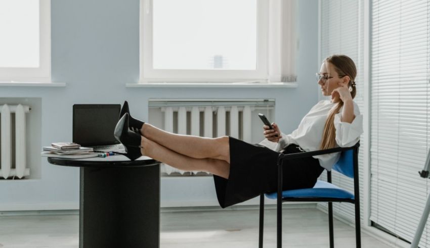 A woman is sitting in a chair and using her cell phone.