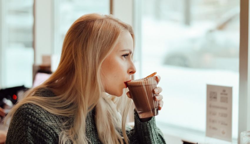 A woman drinking a cup of coffee in front of a window.