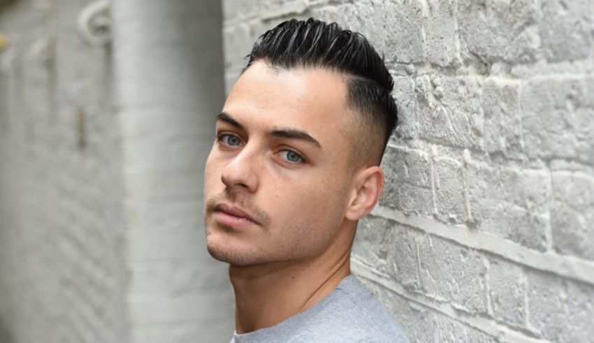 A young man leaning against a brick wall.