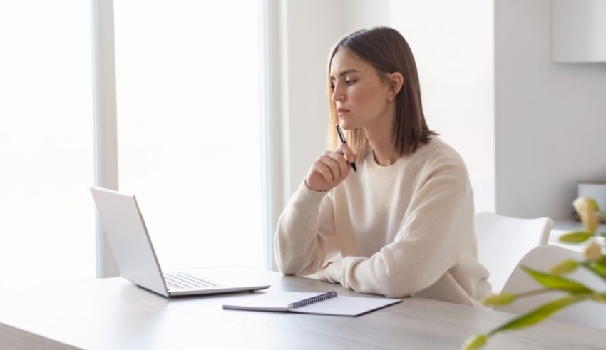 A woman is sitting at a table with a laptop in front of her.