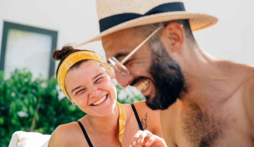A man and woman laughing while sitting on a lounge chair.