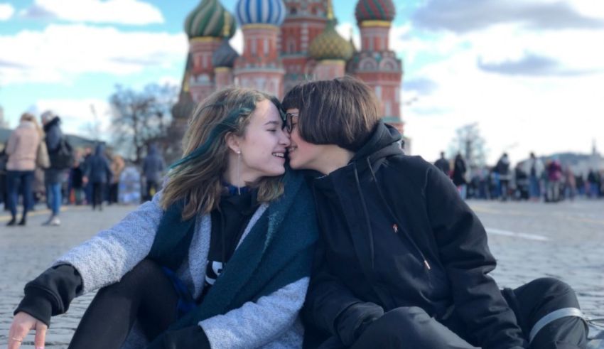 Two girls sitting on the ground in front of st basil's cathedral.