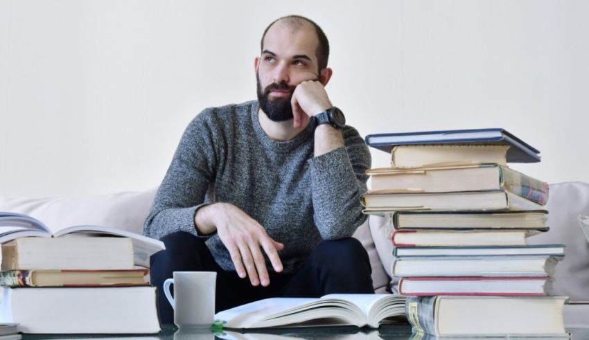A man sitting in front of a pile of books.