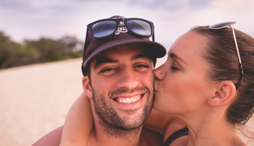 A man and woman kissing on the beach.