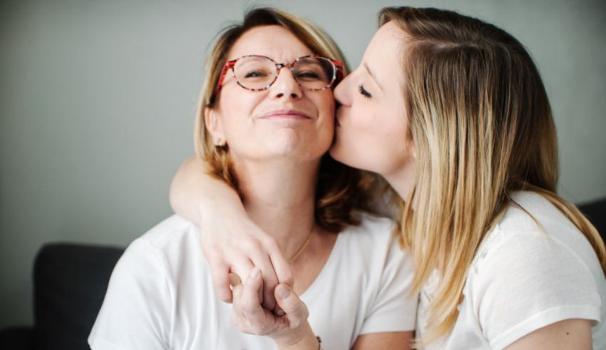 Two women kissing each other while sitting on a couch.