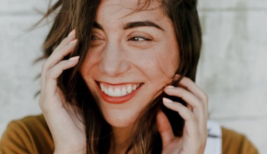 A woman smiling with her hands on her face.