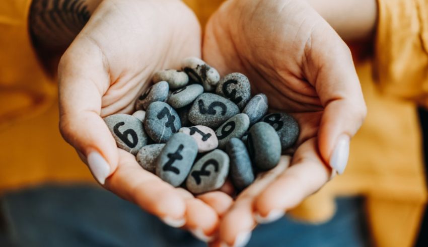 A woman's hands holding stones with numbers written on them.