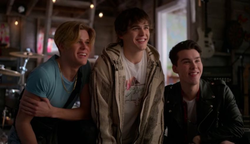 Three young men are smiling while sitting in a room.