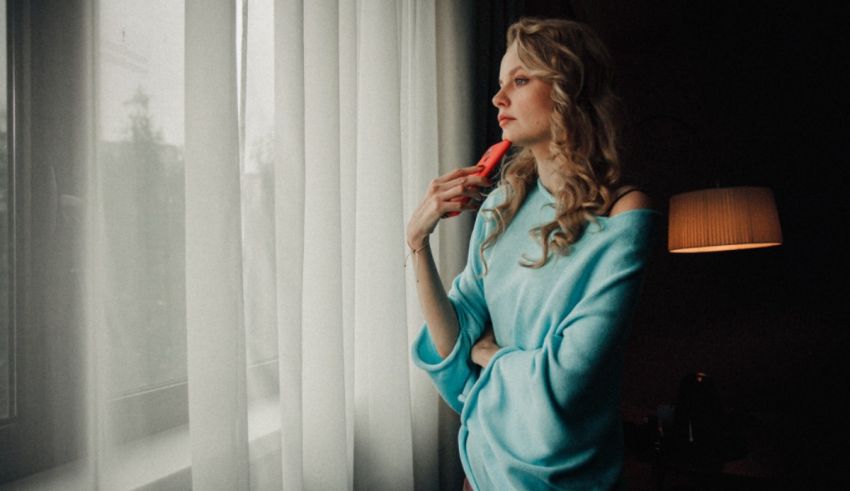 A woman in a blue dress looking out of a window.
