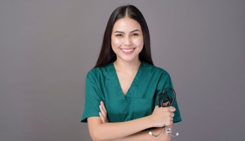 A smiling nurse with a stethoscope posing on a gray background.
