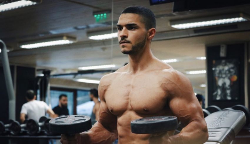 A man in a gym with dumbbells.