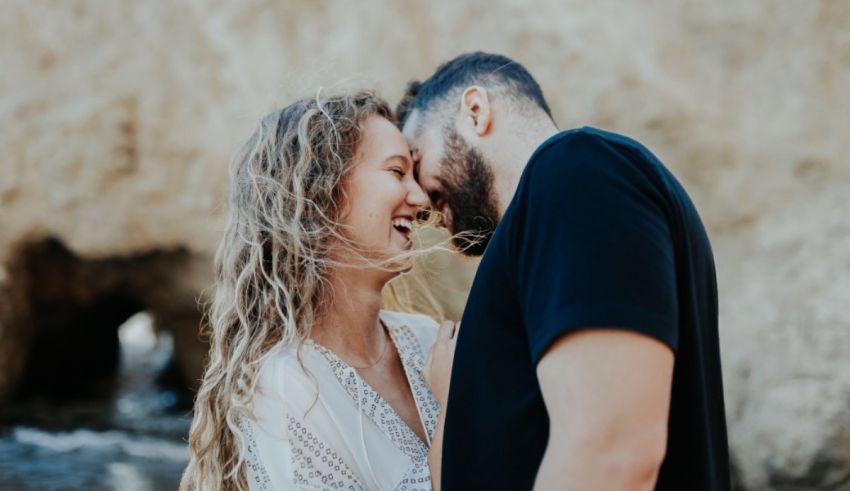 A man and woman hugging in front of a rock.