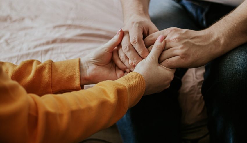 Two people holding hands on a bed.