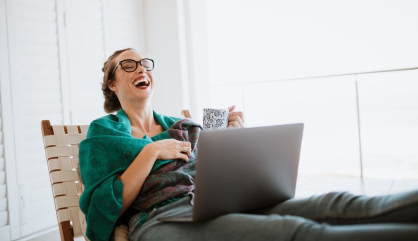 A woman sitting in a chair with a laptop and a cup of coffee.