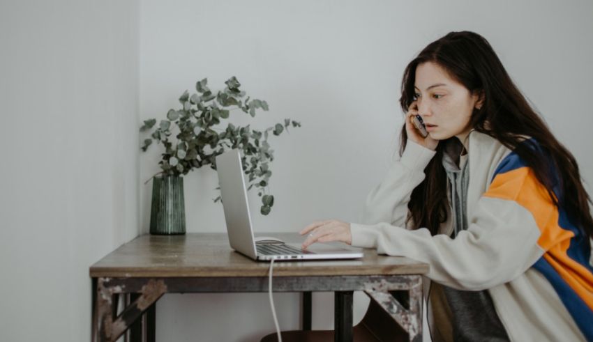 A woman sitting at a table with a laptop on her lap.