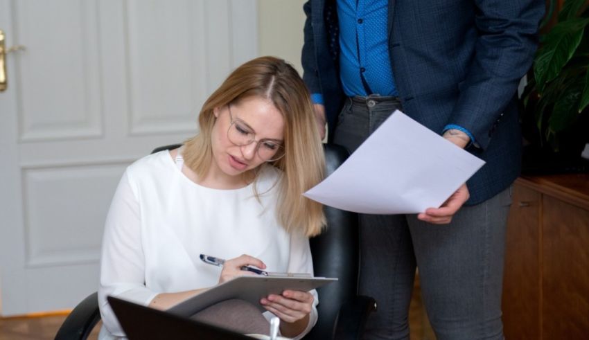 A man and a woman are sitting at a desk in an office.
