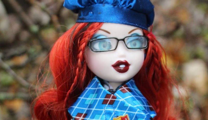 A doll with red hair wearing glasses and a hat.