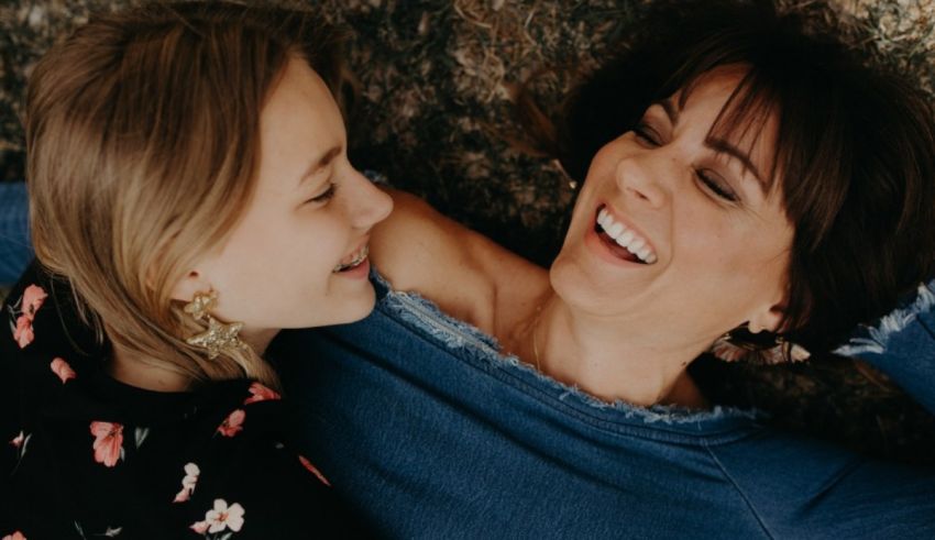 A mother and daughter laying on the floor laughing.
