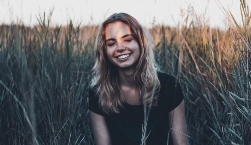 A woman is sitting in a field of tall grass.