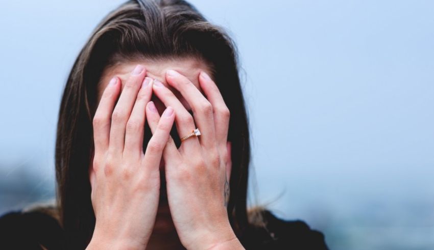 A woman covering her face with her hands.