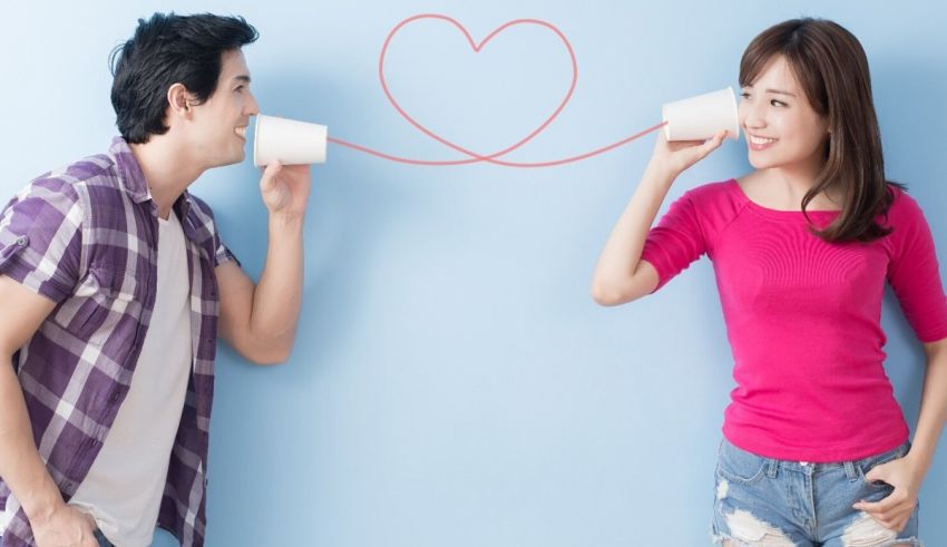 A man and a woman drinking coffee from a cup with a heart drawn on it.