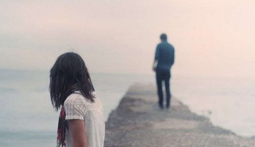 A man and woman standing on a dock looking at the ocean.