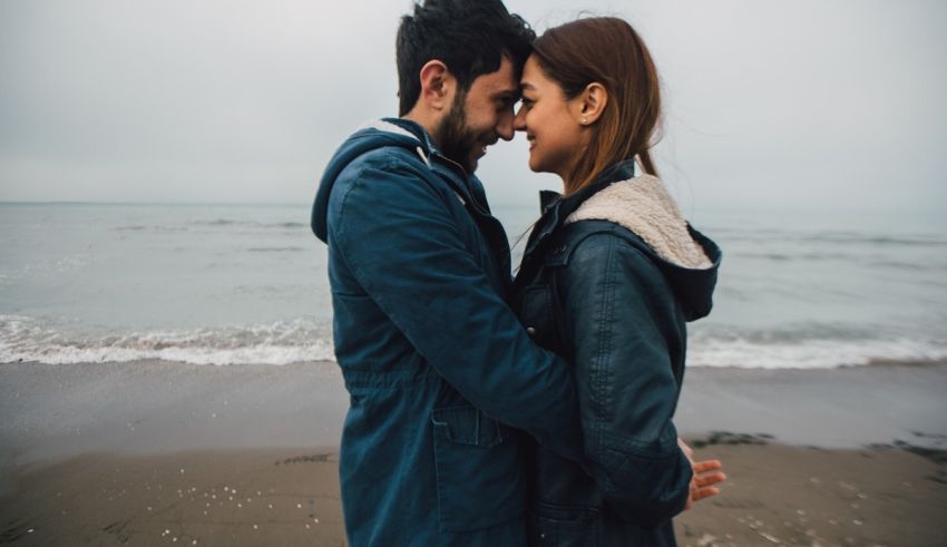 A man and woman are embracing on the beach.