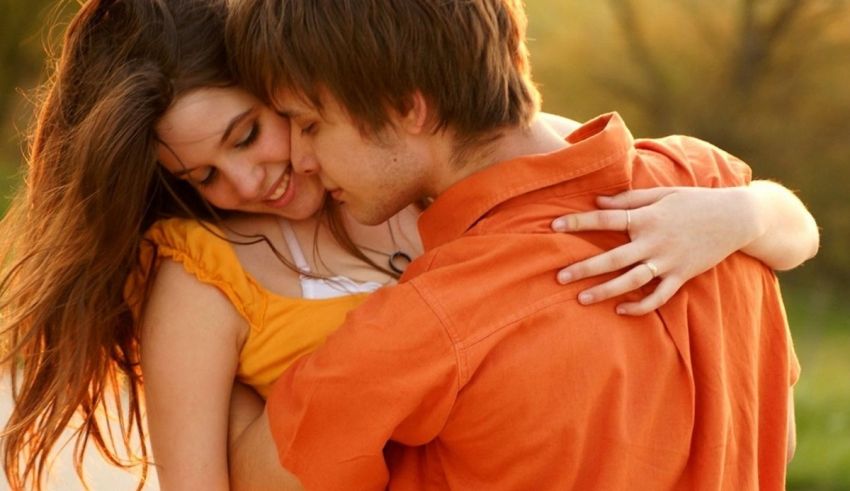 A man and woman hugging each other in the park.